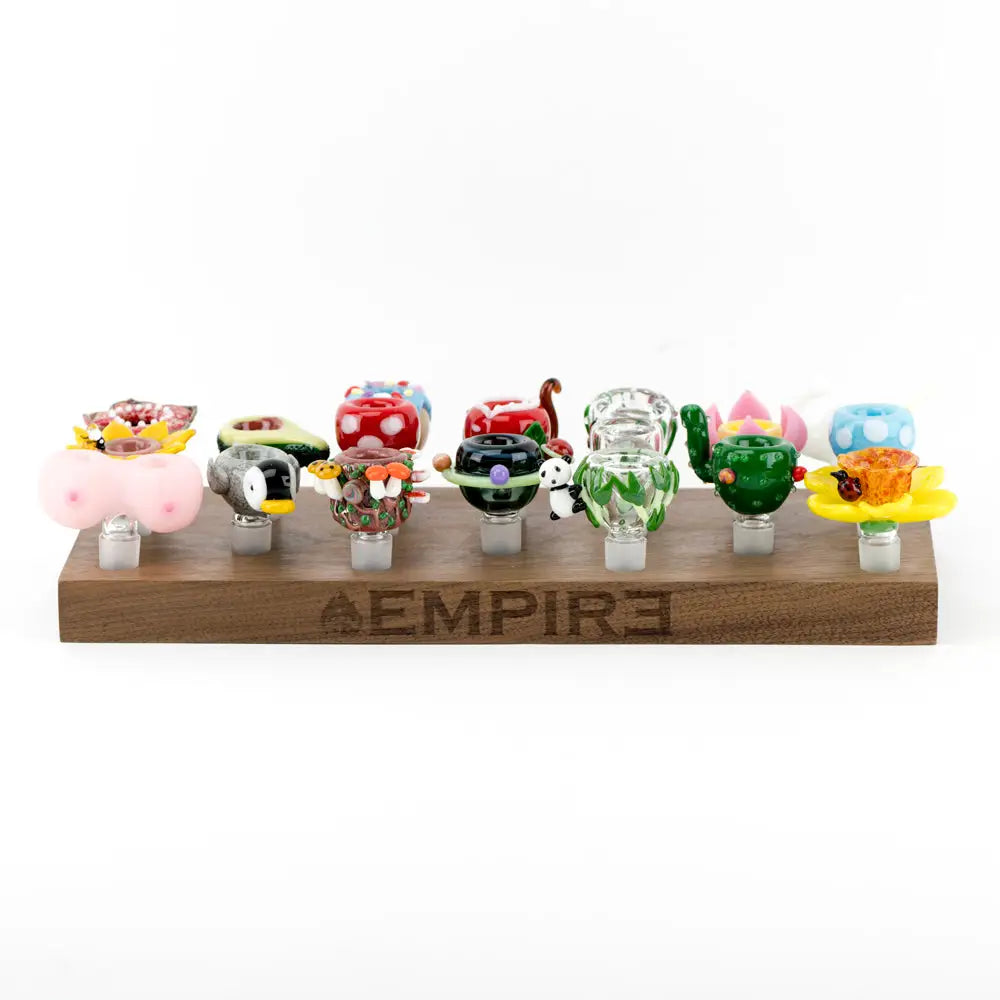 Colorful hand-blown glass bowl pieces in whimsical designs on Empire Wooden Bowl Piece Display