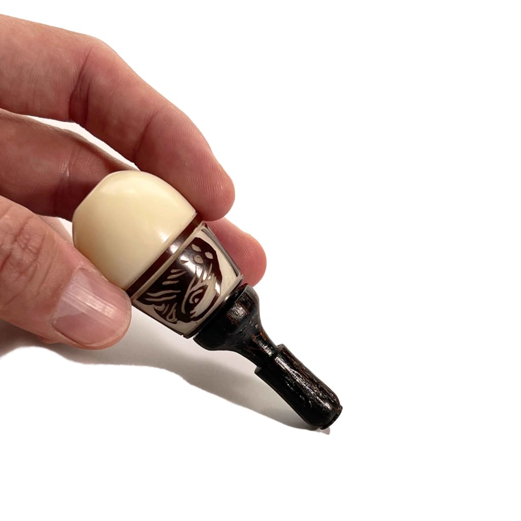 Bottle opener with white ceramic handle held near Colombian Tagua Seed hand pipe for discreet smoking