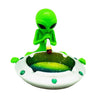 Green alien figurine smoking from UFO-shaped ashtray for an alien smoke session