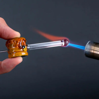 Hand holding Empire Glassworks poker wand beehive glass hand pipe heated by torch
