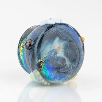 Empire Glassworks terp jar Across the Universe: translucent blue glass figurine with iridescent swirls, black eye, and delicate white floral accents