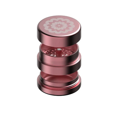 Rose gold metal grinder from Flower Mill’s Generation Standard collection with glass hand pipe