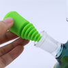 Bright green silicone cleaner plug with ridged design being inserted into a glass water pipe