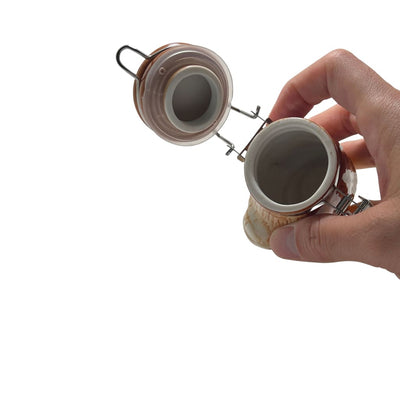 Hand opening a glass jar with a hinged lid, perfect for Ceramic Storage Jars and elegant home decor