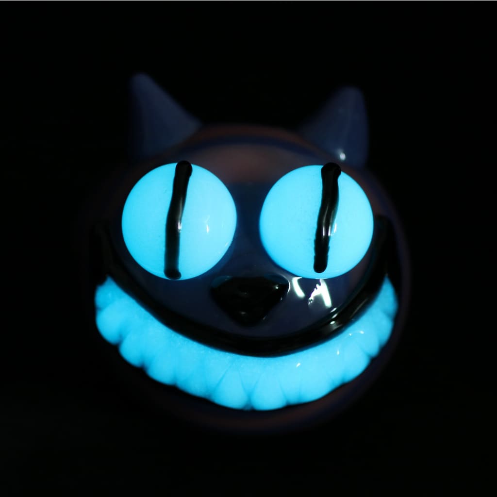 Glow-in-the-dark Cheshire Cat glass marijuana pipe with blue eyes