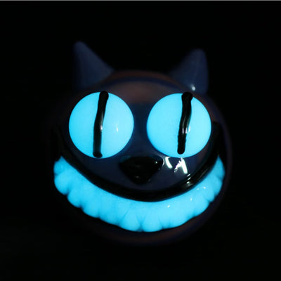 Glow-in-the-dark Cheshire Cat glass marijuana pipe with blue eyes