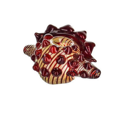 Glass hedgehog figurine with red spikes in borosilicate glass, displayed near conch shell pipe