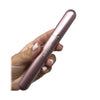 Hand holding metallic pink aluminum doob tube weed pipe with white-painted nails