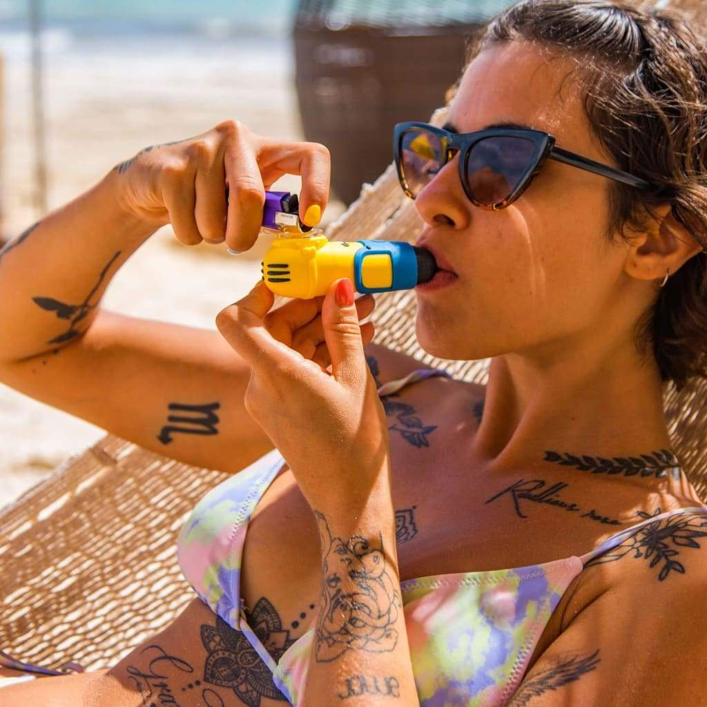 Woman with sunglasses using a colorful and fun Minion silicone pipe hand vape device
