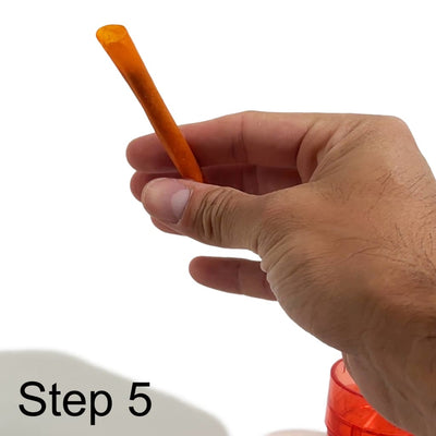 Orange plastic straw held between fingers for filling in portable transparent pre-roller